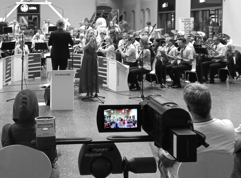 fotohaefeli videokamera auf stativ nimmt das live band SBB orchester in der basler SBB bahnhofhalle auf